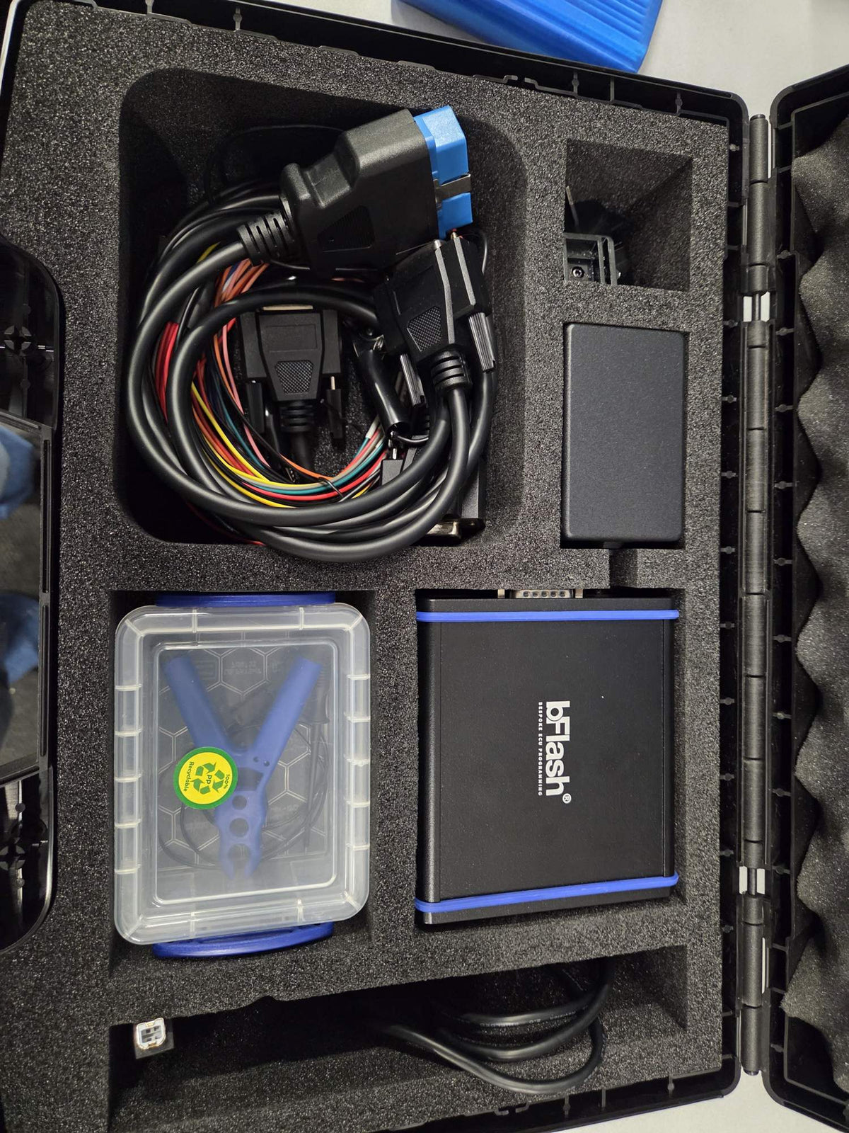 Top view of bFlash ECU programming kit with interface module, cables, power supply and probe box in foam case
